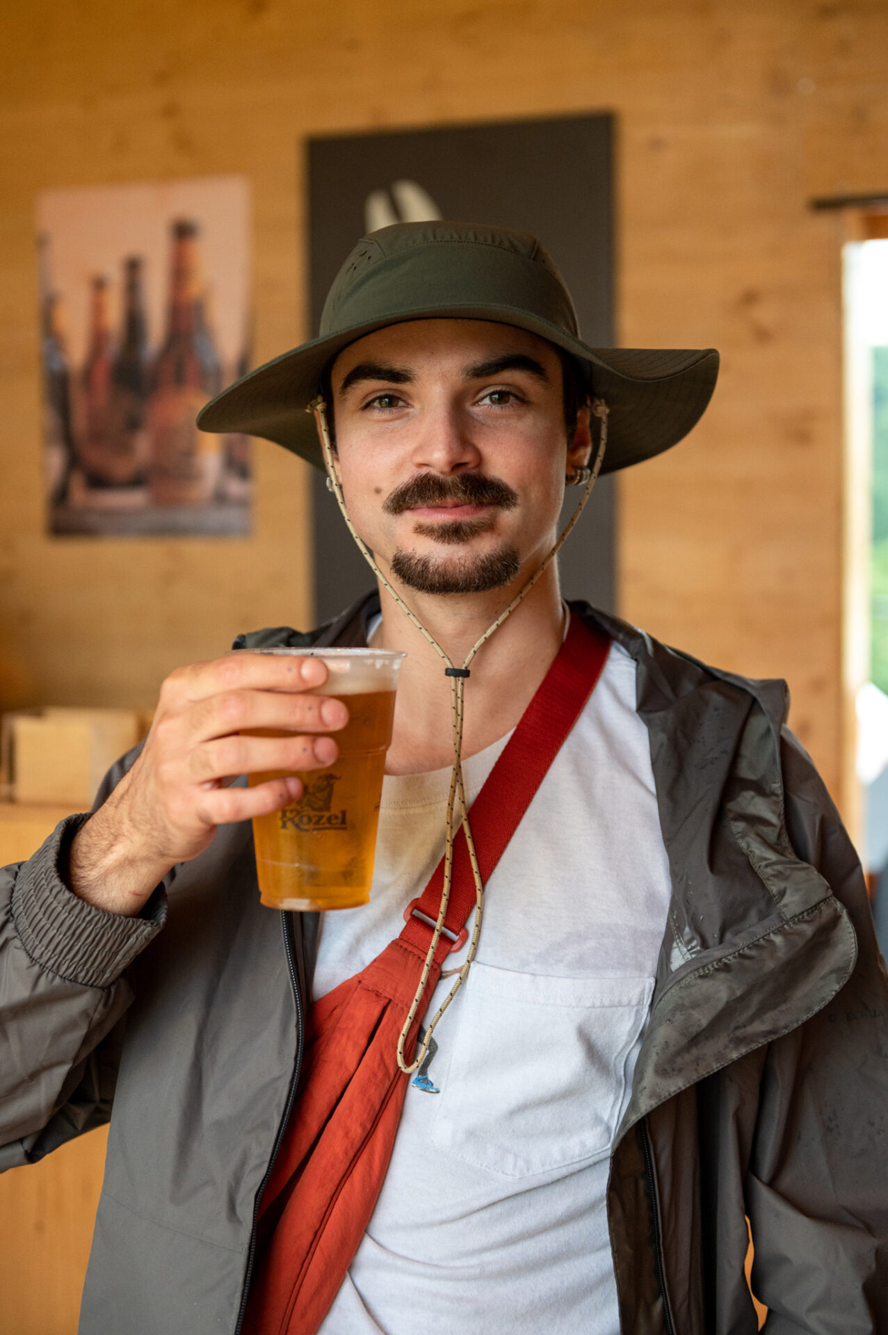 a man wearing a hat and holding a glass of beer